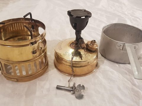 The Svea 123, the Stove That Refuses to Die A brass Svea 123 backpacking stove disassembled with its windshield, burner, and aluminum pan