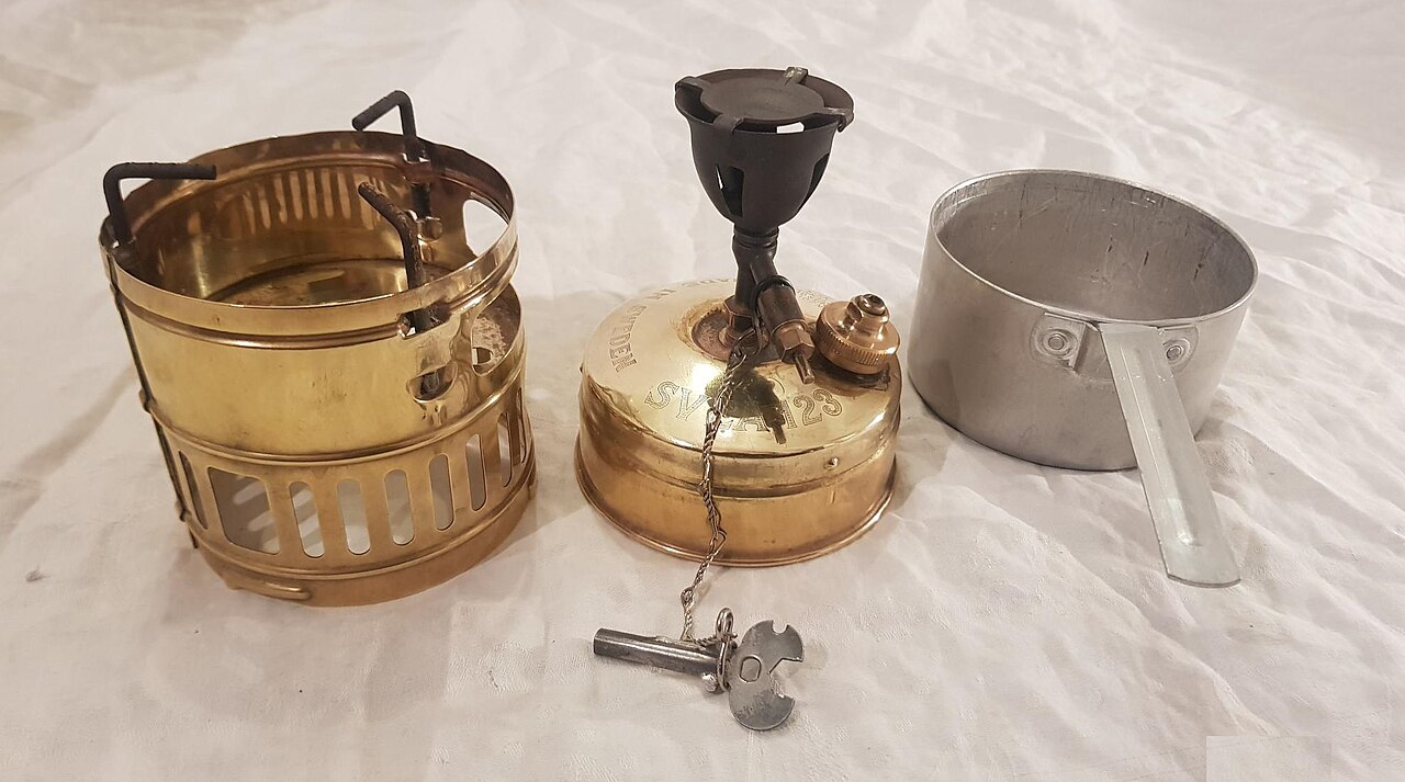 A brass Svea 123 stove with its windshield and pan, packed compact